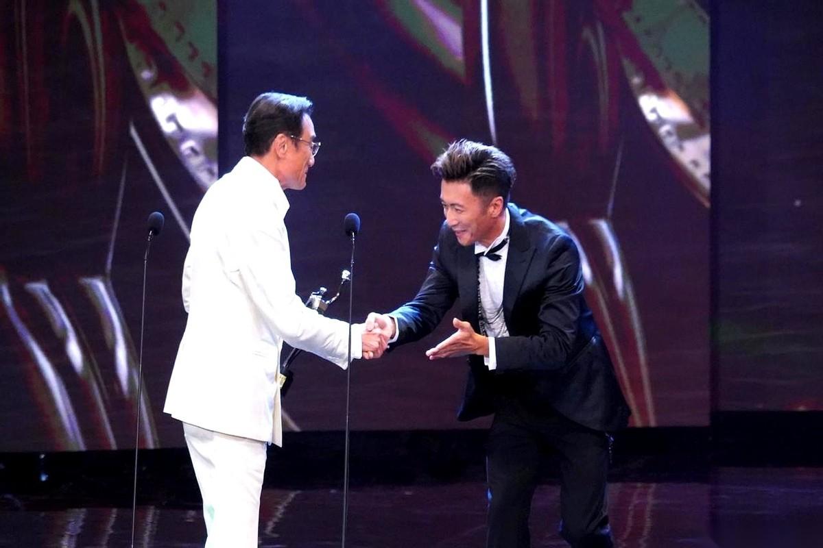 颁奖礼现场，谢霆锋手里稳稳地托着奖杯，目光正盯着台下。此时，梁家辉正从座位上起