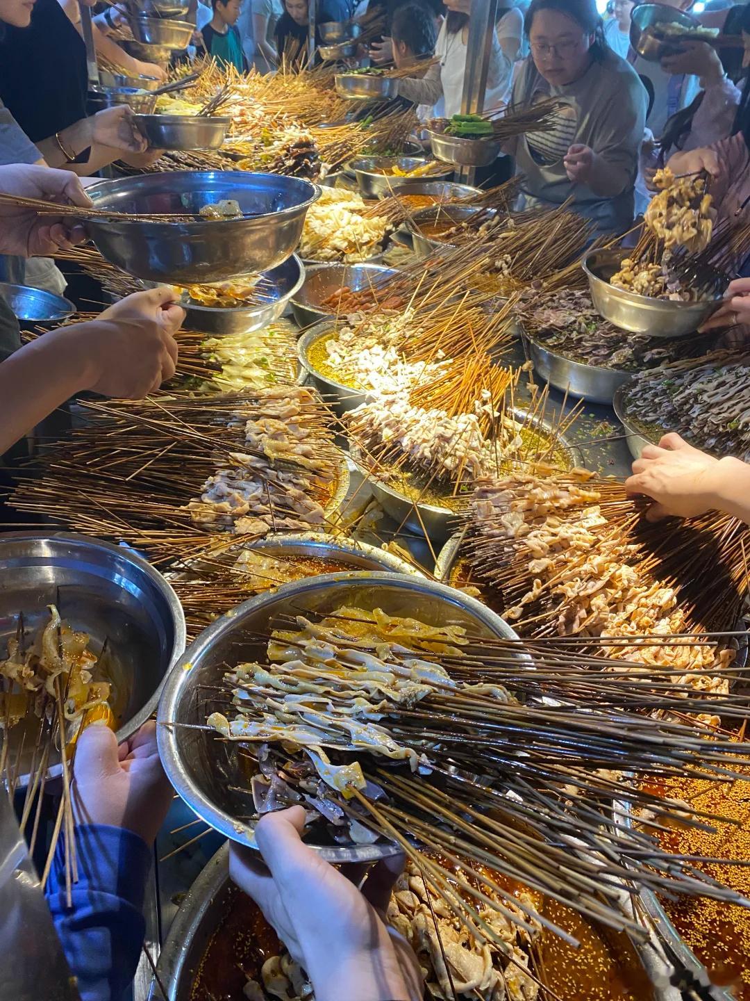 成都的钵钵鸡，第一个想到的应该就是他家，满满当当的铁盆放满了各种菜，一圈人围着拿