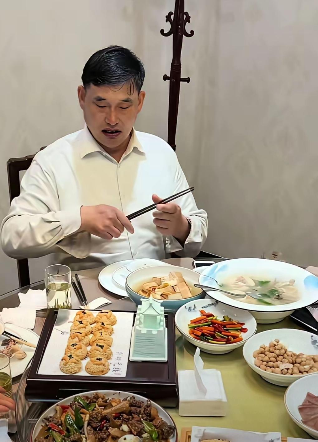 这位大哥正在用筷子夹菜呢。满汉全席也不如大衣哥在老家吃咸菜馒头香。大衣哥的出场费