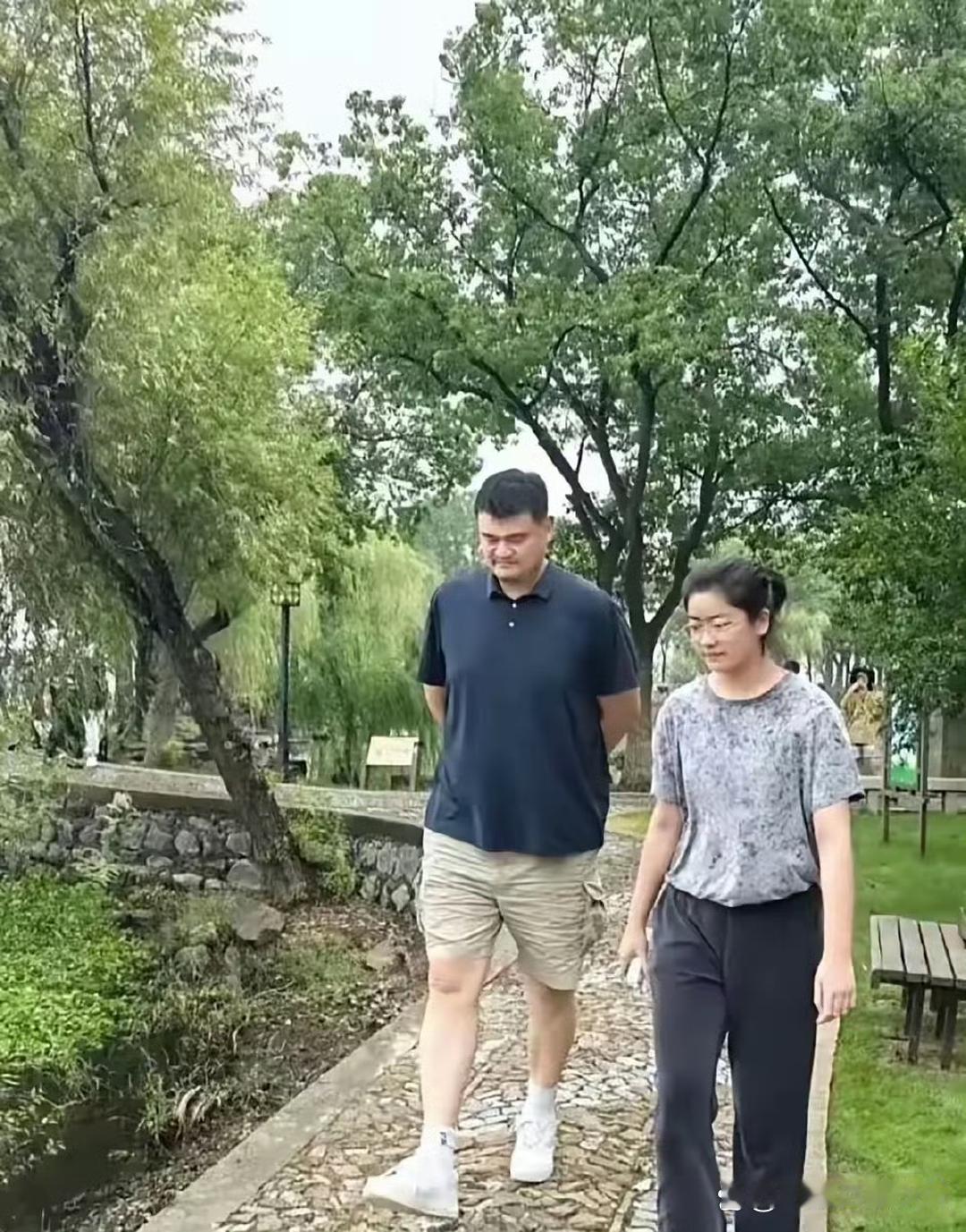 姚明陪女儿公园散步，画面超温馨！父女俩并肩走在林荫小道上，神态、眉眼竟如出一辙，