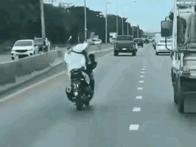 大哥驾驶摩托车骑行，以为技术很好。放开右手骑行还不知足，又把右脚抬起。这下好了，