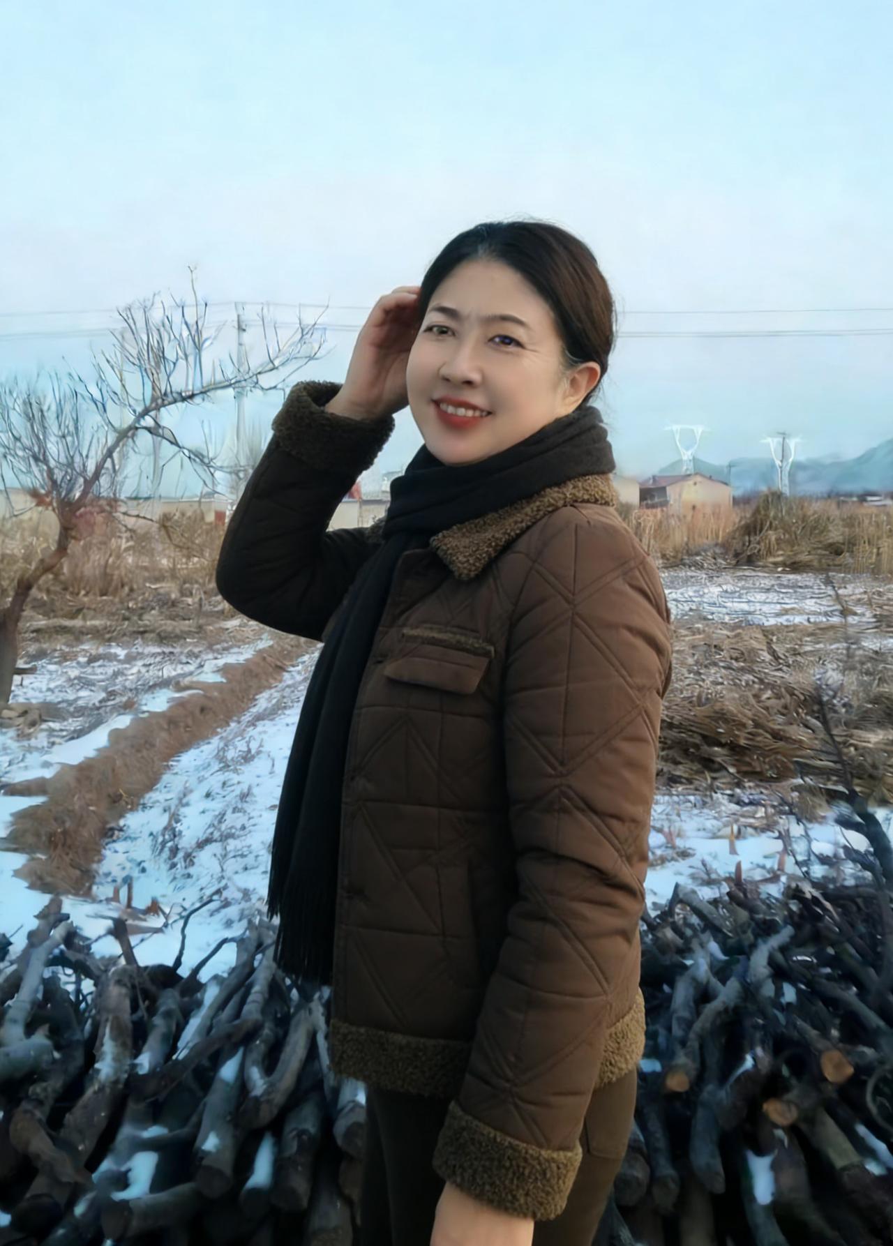 朔风卷雪满野丘，寒日苍苍照远畴。棕褐棉衣遮瘦影，玄色围巾绕玉头。荒林树秃栖寒