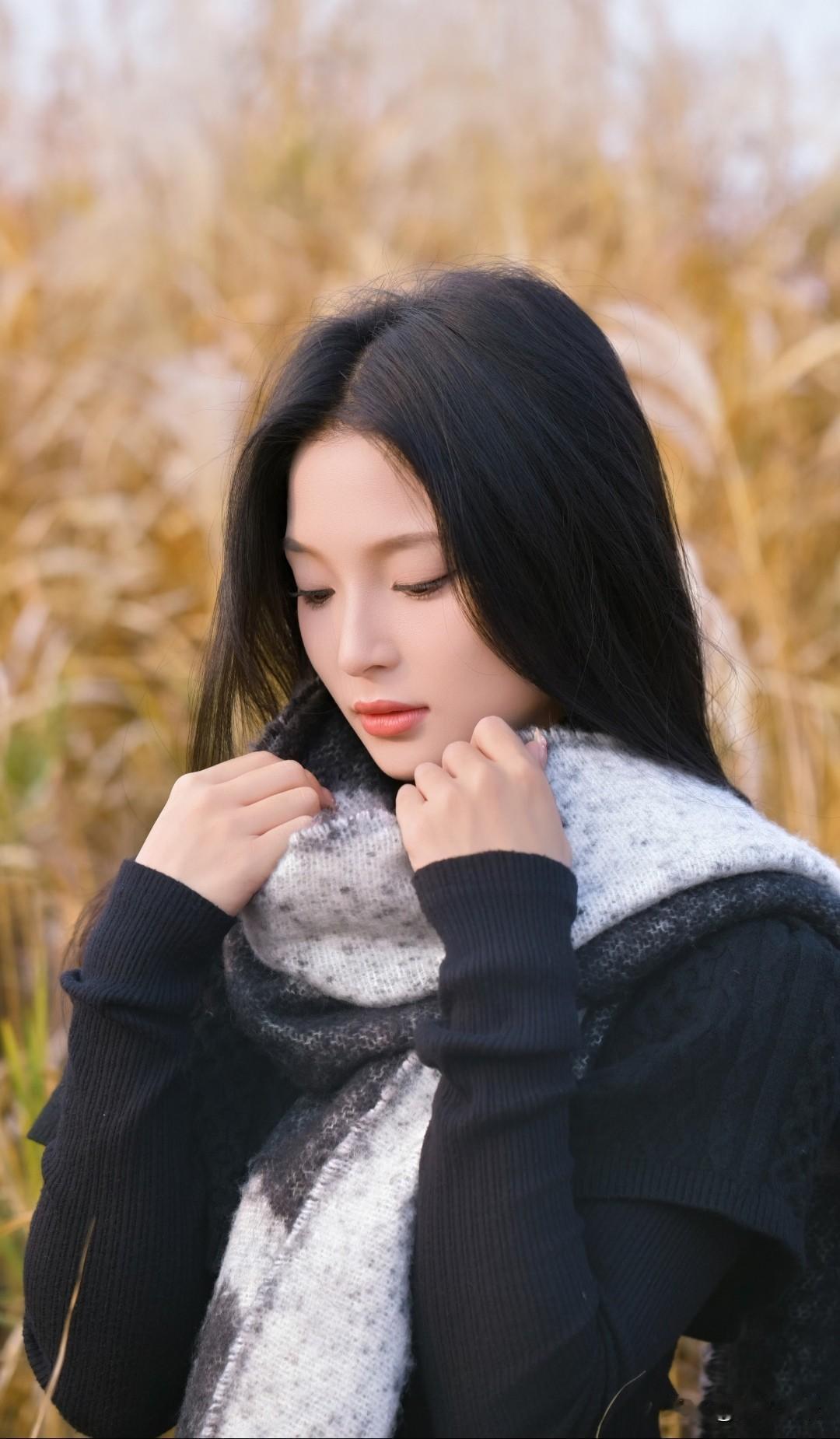秋日暖阳下，黑发少女轻抚围巾，沉思静谧。