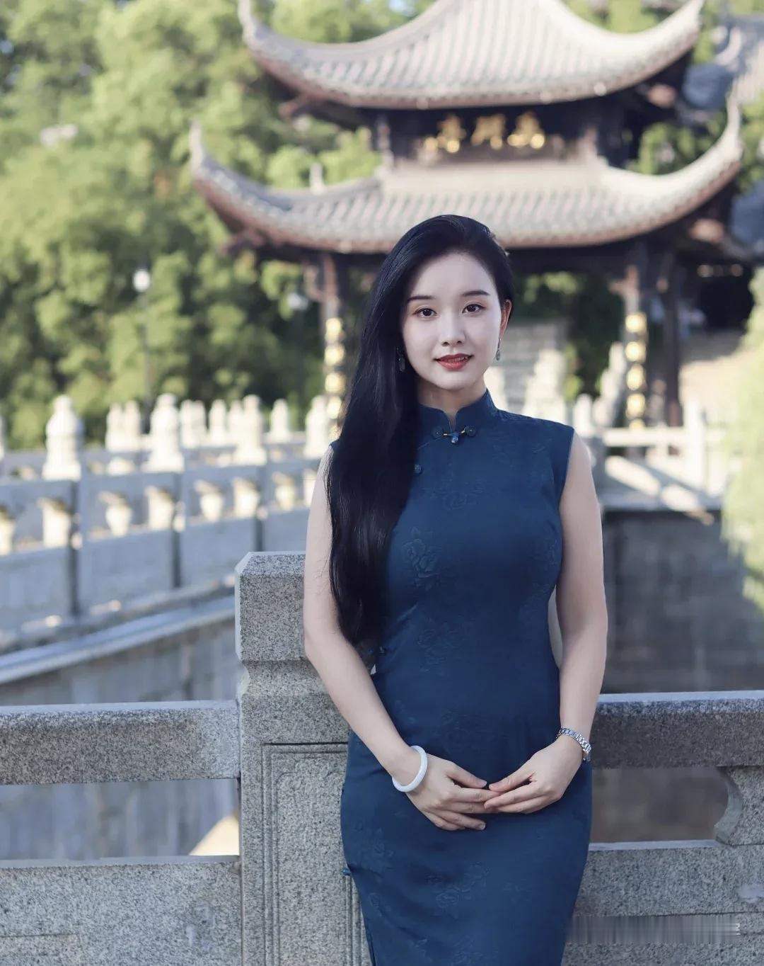 这位女士穿着旗袍，站在古建筑前。
