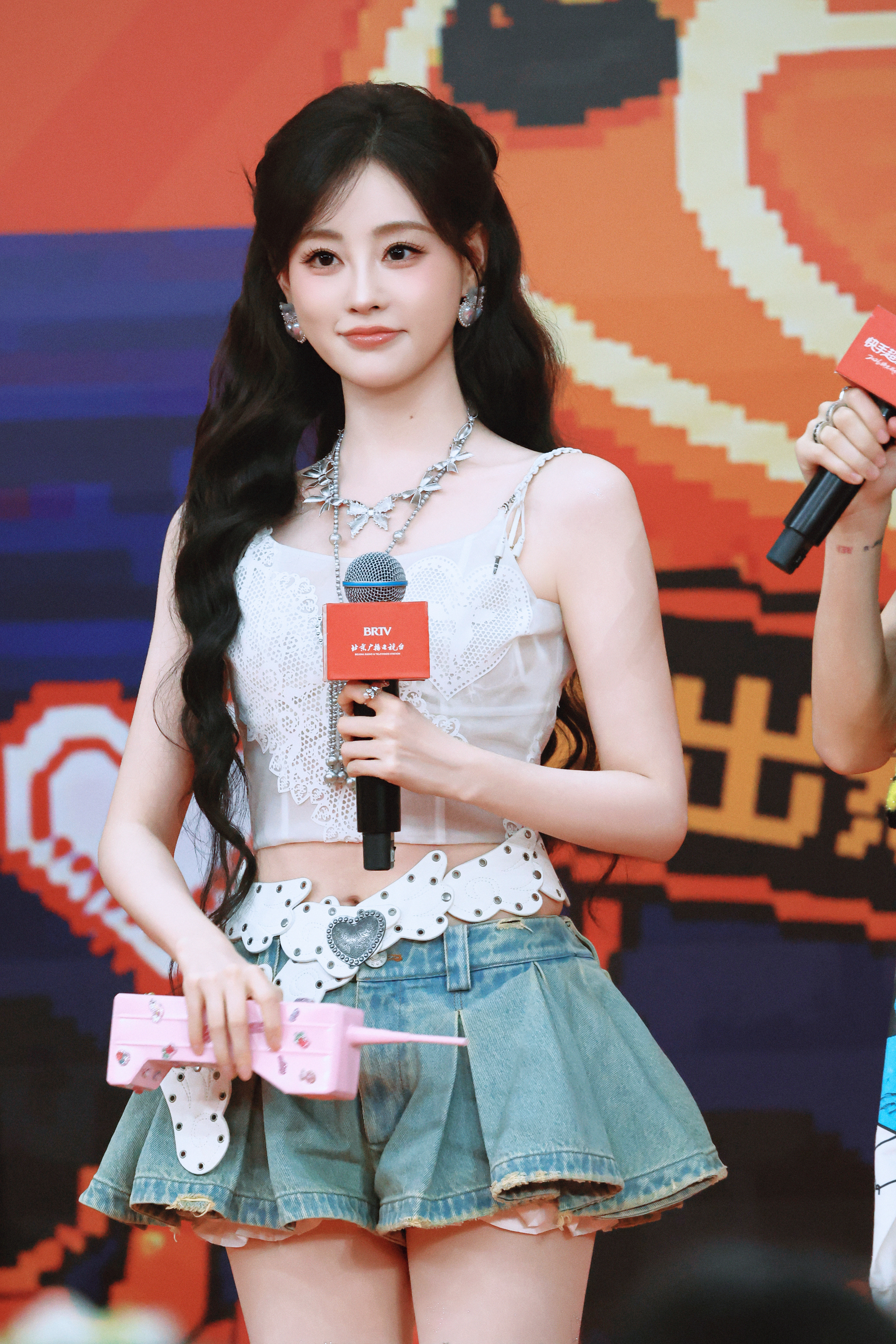 祝绪丹·纯白蕾丝吊带勾勒灵动腰线，牛仔百褶短裙搭配毛绒长靴，甜酷元气的舞台造型扑面而来。​