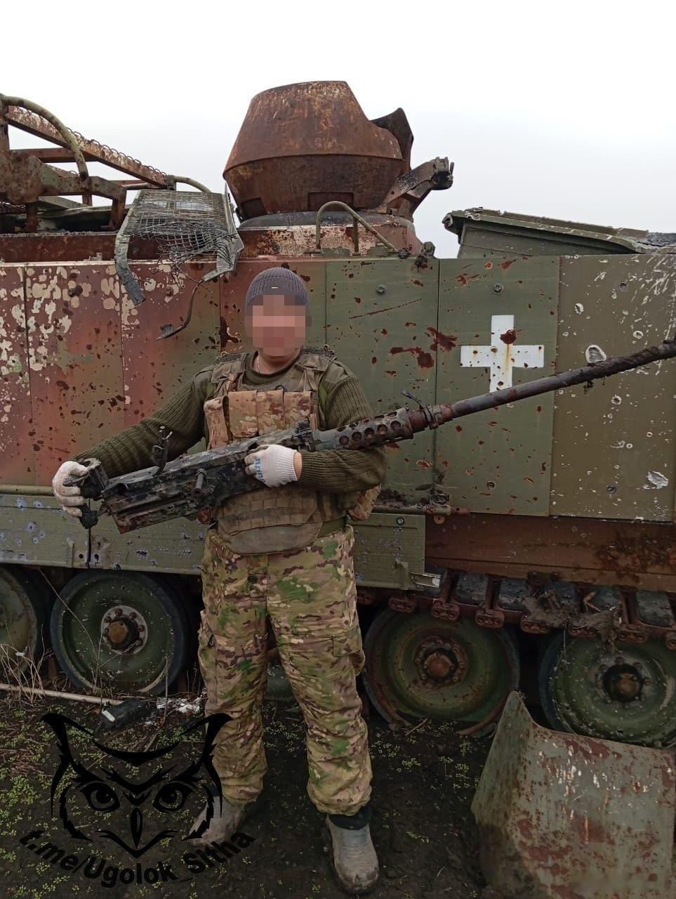 俄罗斯士兵手抱缴获的M2老干妈.50口径重机枪，背景是被击毁的北约YPR-765