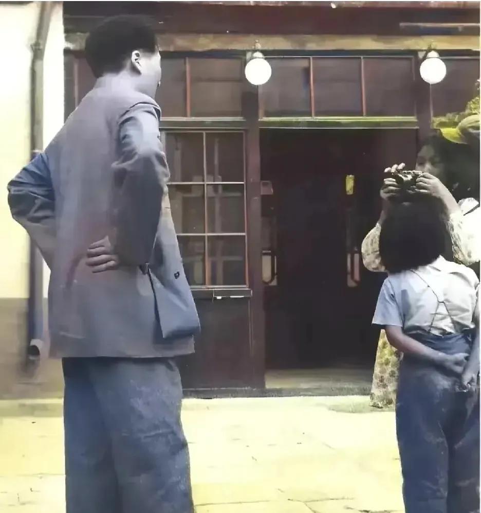 这张老照片，记录了伟人和家人温馨一幕。李敏拿着相机给父亲拍照，一个戴军帽的人在指