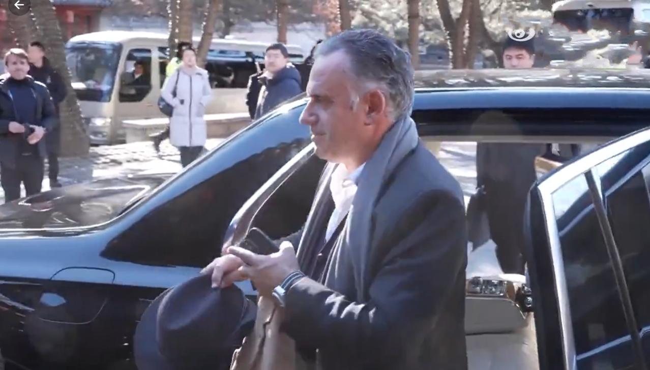 乌拉圭总统专车抵达长城脚下，胳膊上搭着一件咖色外套手里拿着黑色礼帽，让人没想到的