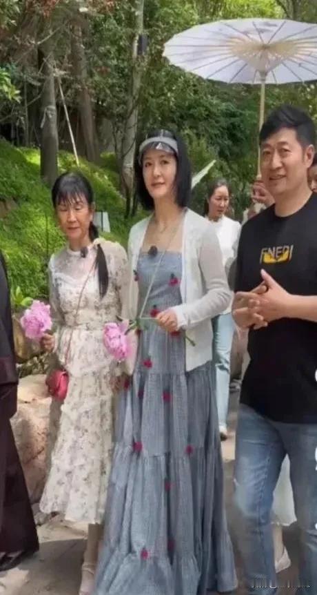 谢娜身着灰色裙子，留着齐肩短发，与母亲一同逛公园。谢娜看起来和母亲很相像呢，她的