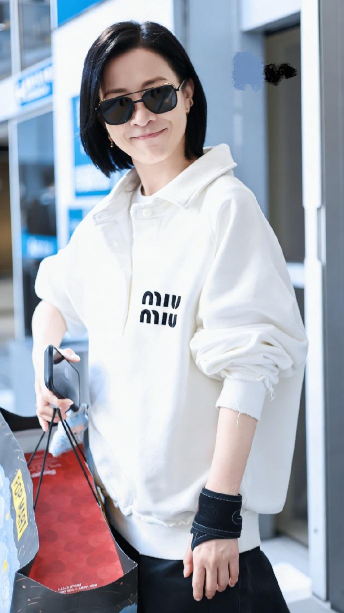 最近佘诗曼现身机场，她里面穿白色打底衫，外面套着米白色的字母风卫衣，两件衣服叠穿