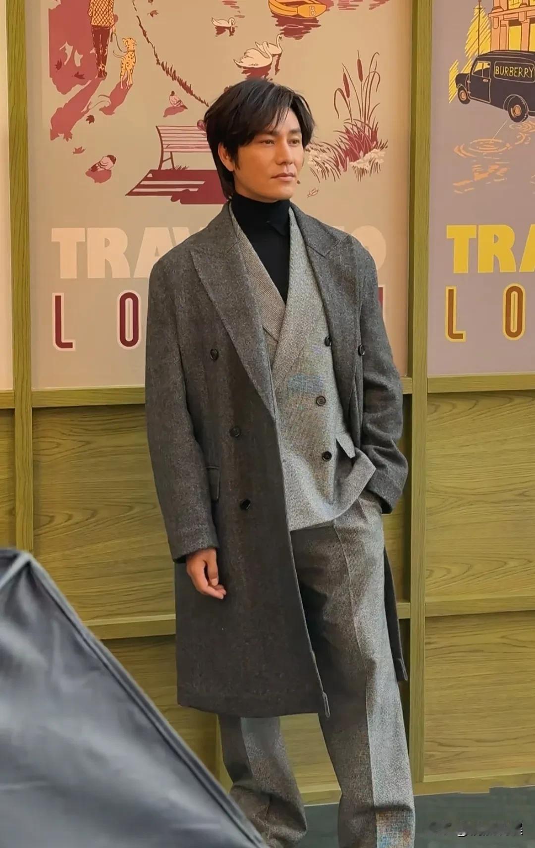 陈坤现身北京出席活动，穿着灰色西装搭配长风衣，头上戴着假发套，眉毛往上瞪，眼睛睁