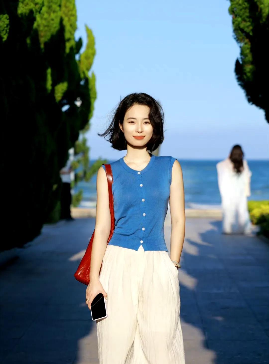把步子踩进海风里，蓝衫白裤晃着闲意，红棕的包袋坠着日落的余温。海在身后铺成温柔的