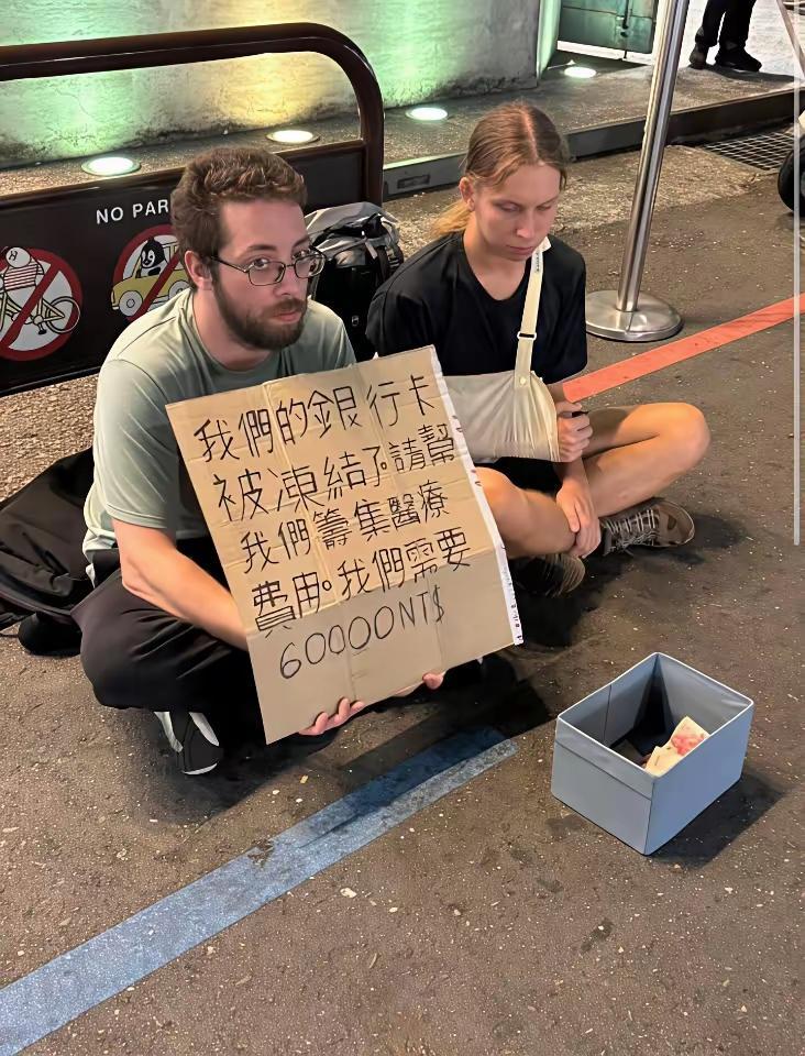两老外在街头举牌求助，说是银行卡被冻结了，女伴受伤需要治疗，所以希望大家帮忙帮他