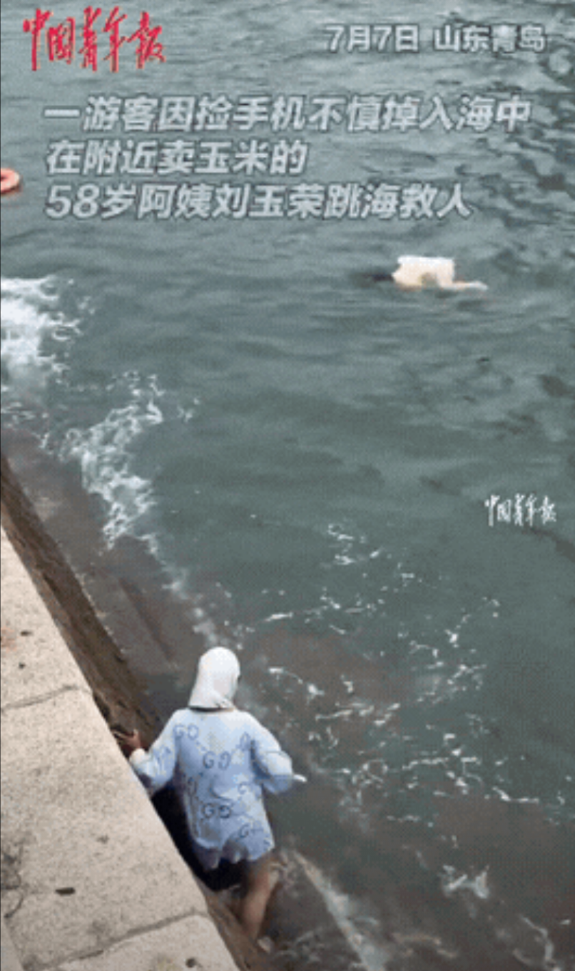“这位大妈火了！”山东青岛，一女生岸边拍照，手机不小心掉入海中，捡手机被浪拍打进