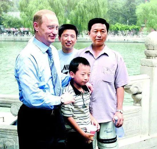 十八年前普京在北京市西城区北海公园与小男孩一家人的合影如下图（普京与小男孩彭