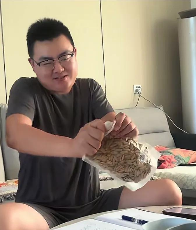 郭威使劲撕开古法瓜子，终于撕成功，然后开心地对着镜头笑了…古法瓜子相当有魅力，