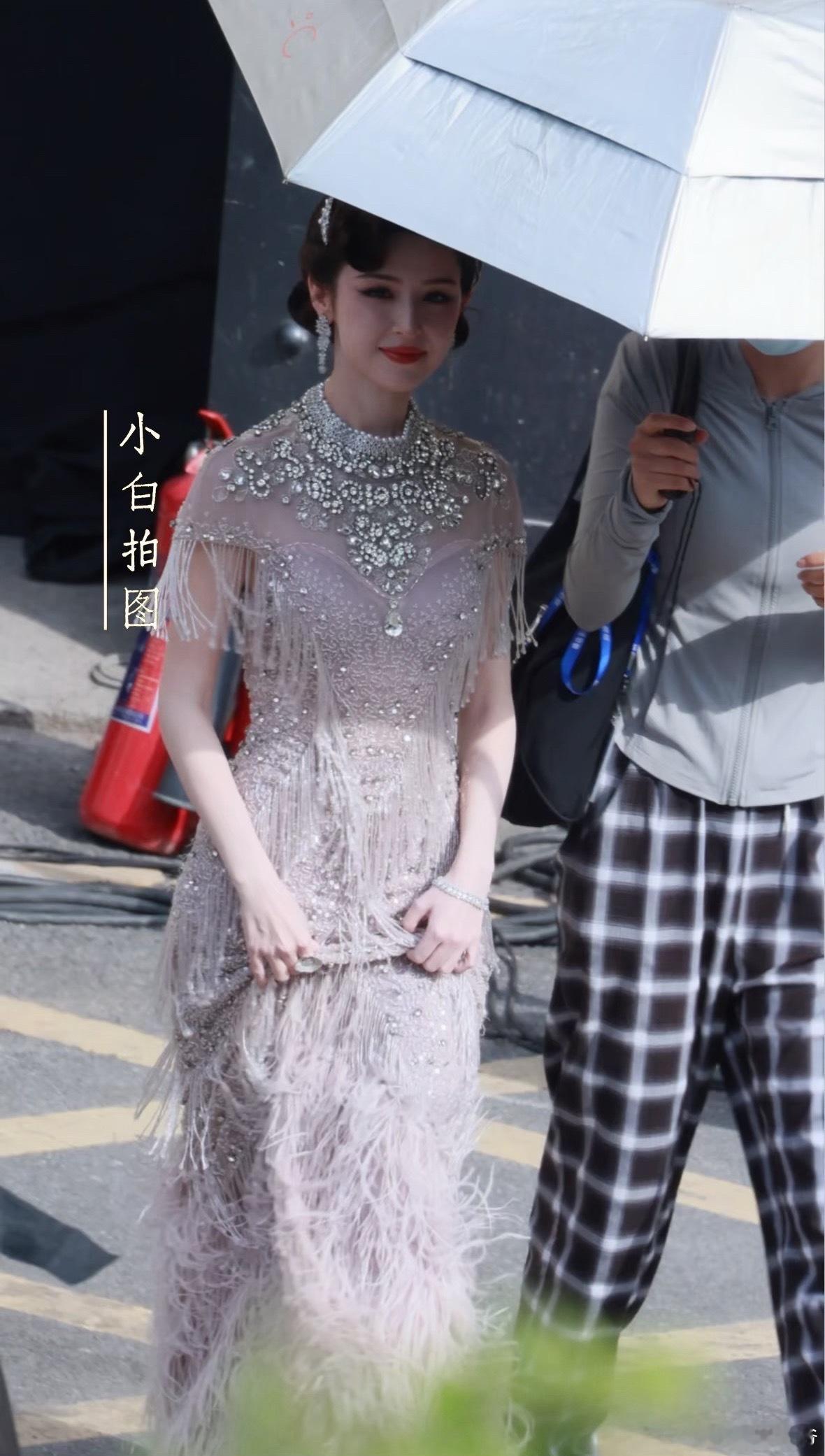 哈妮克孜露背旗袍华丽的羽毛裙摆在灯光下熠熠生辉，每一步都流露着高贵气质，仿佛是