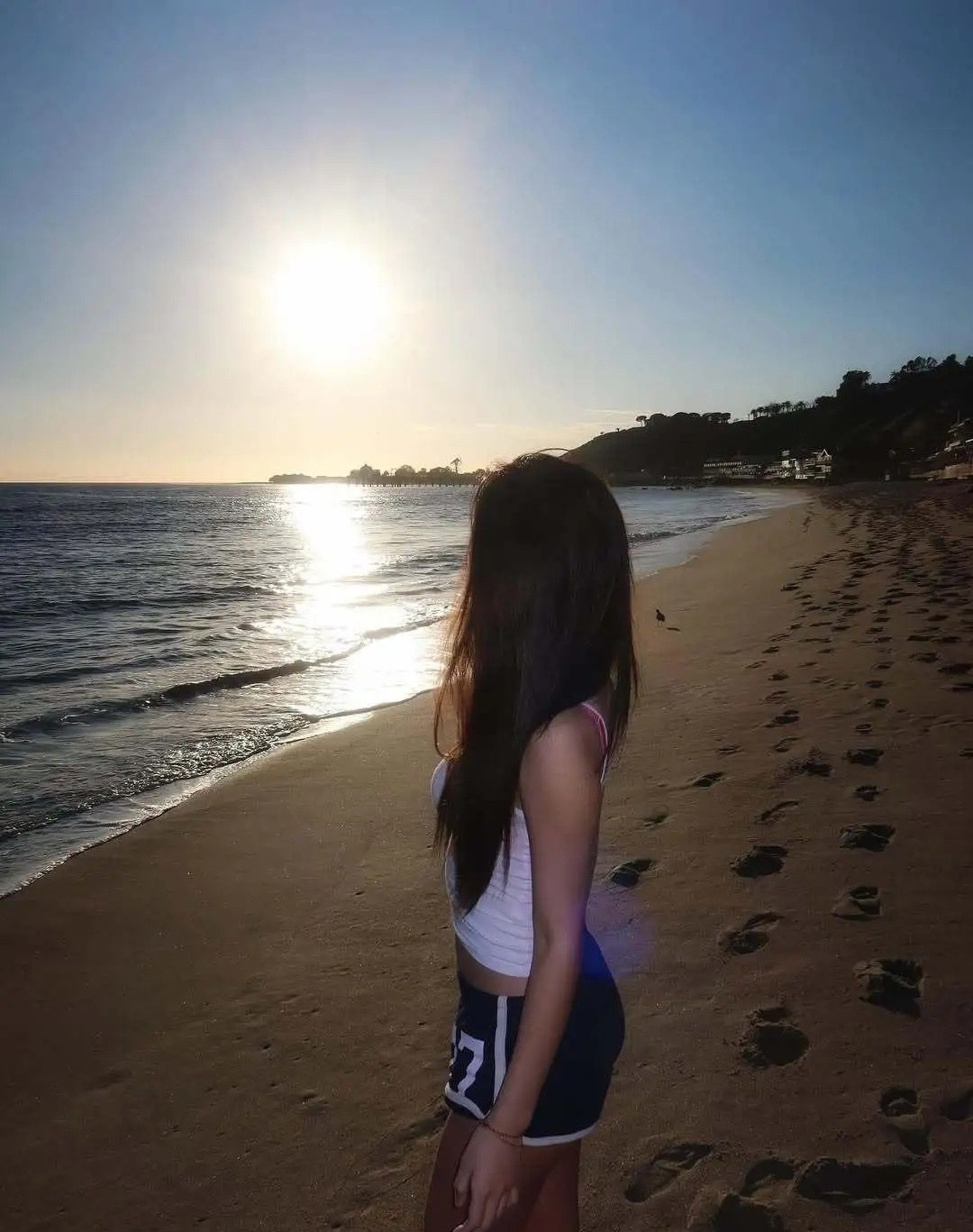 小S20岁大女儿在美国海边看日落，她穿着吊带衫和短裤在沙滩上享受着日光浴，全身皮