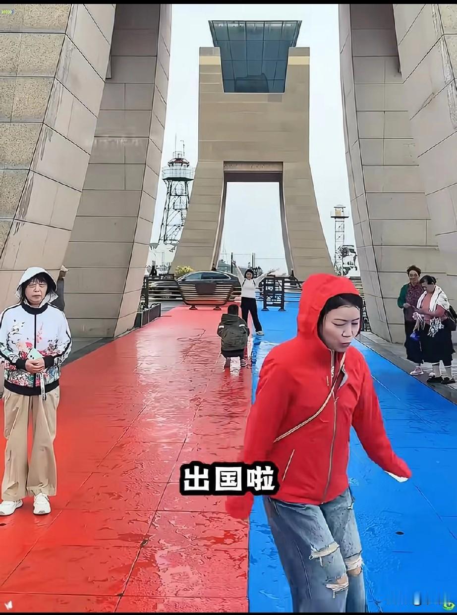 女子和朋友去边境旅游，看着国境线，她就开始调皮起来，跳到了蓝色色的面，她