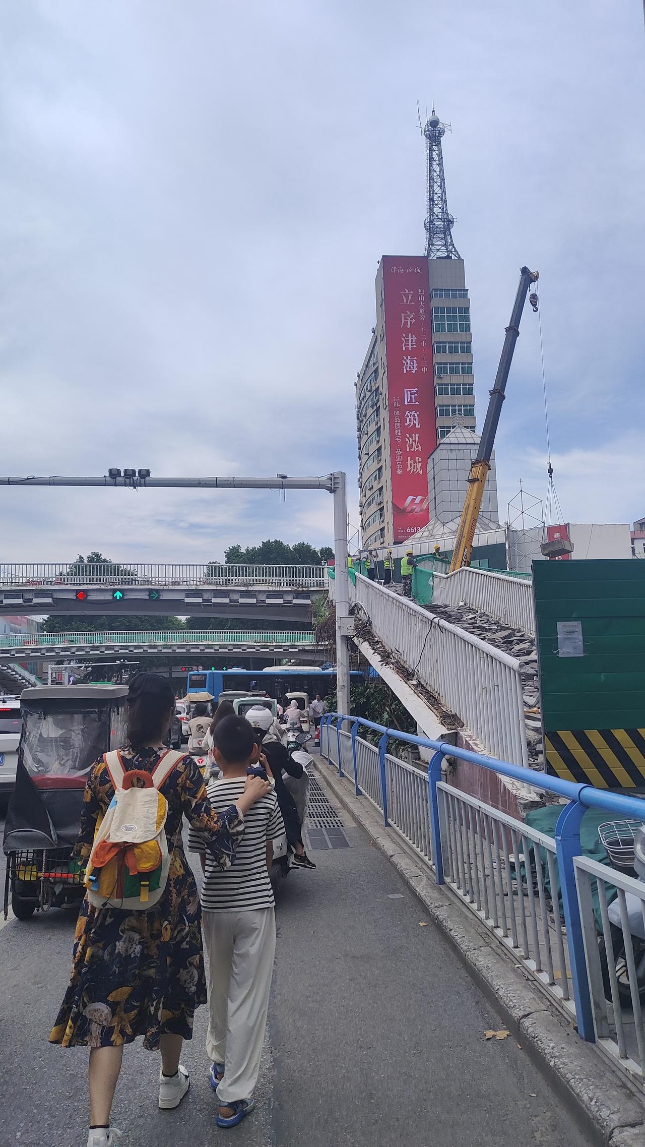 南阳市新华路、人民路口附近天桥正在提升改建。能看到挖掘机在现场施工。当然，下边