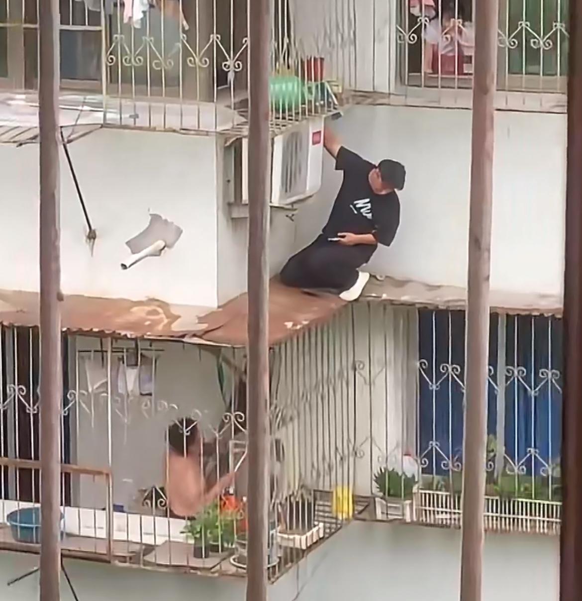 好一对卧龙凤雏，黑衣男子上面修空调，赤膊男子拿杆子下面捅。黑衣男子作为空调维修人