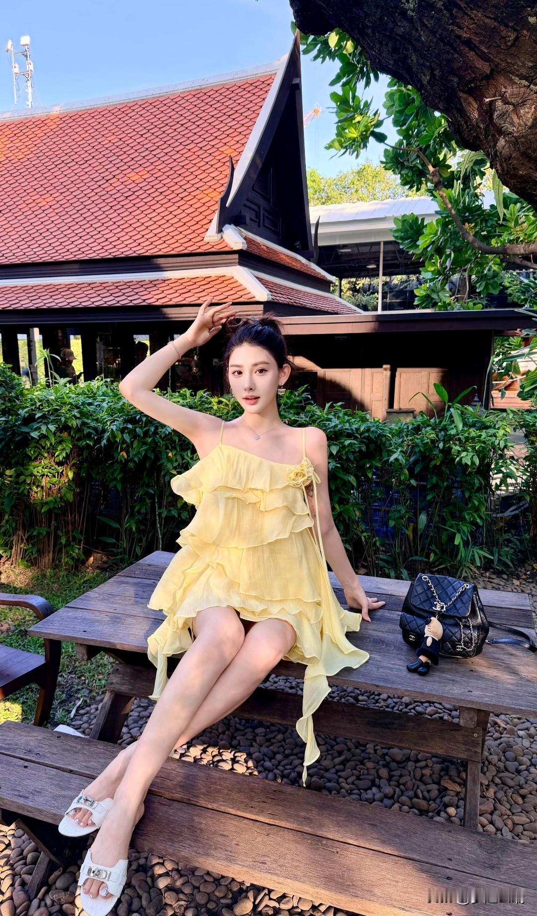 阳光明媚的午后，美女穿着黄色连衣裙，坐在木桌旁，享受宁静时光。