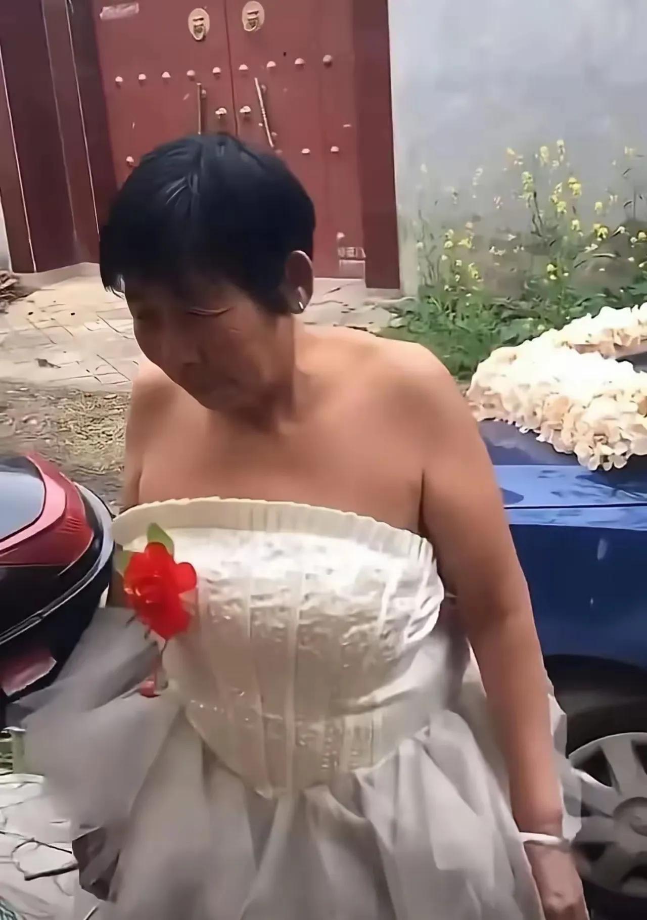 这是二婚现场吗？大妈穿着白色抹胸婚纱，胸前别着小红花，就是模样磕碜点。满脸皱纹，