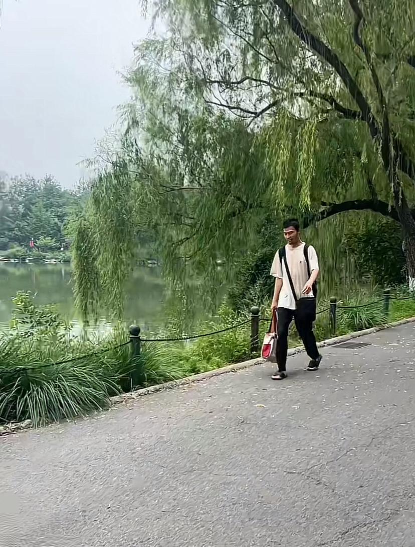 同学又碰到韦神了，这次在一个湖边，穿着大拖鞋，走得特匆忙，身上背个包，前面挎个包