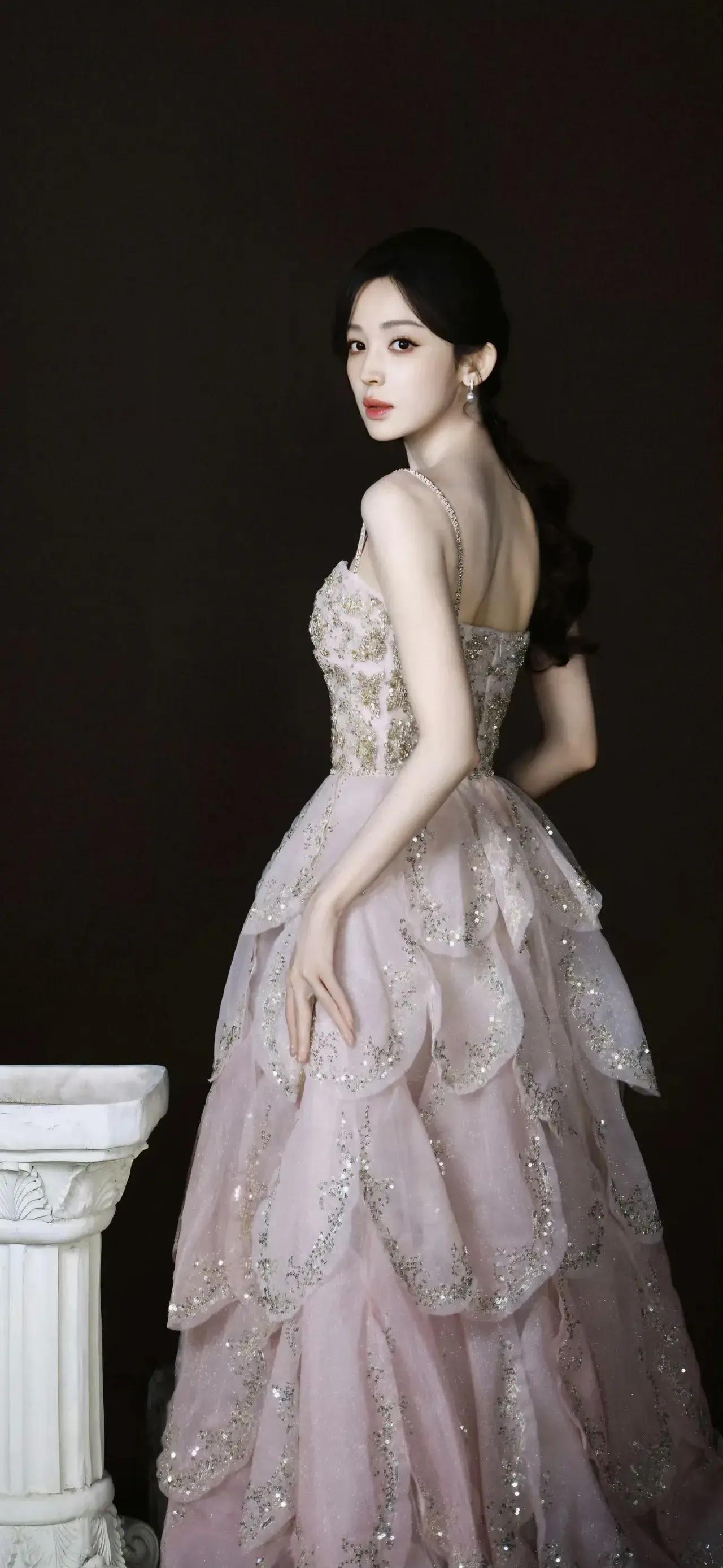 烟粉纱裙缀满鎏金碎闪，层叠裙摆如盛放的花瓣，碎钻在暗调里漾开柔光。古力娜扎一颦