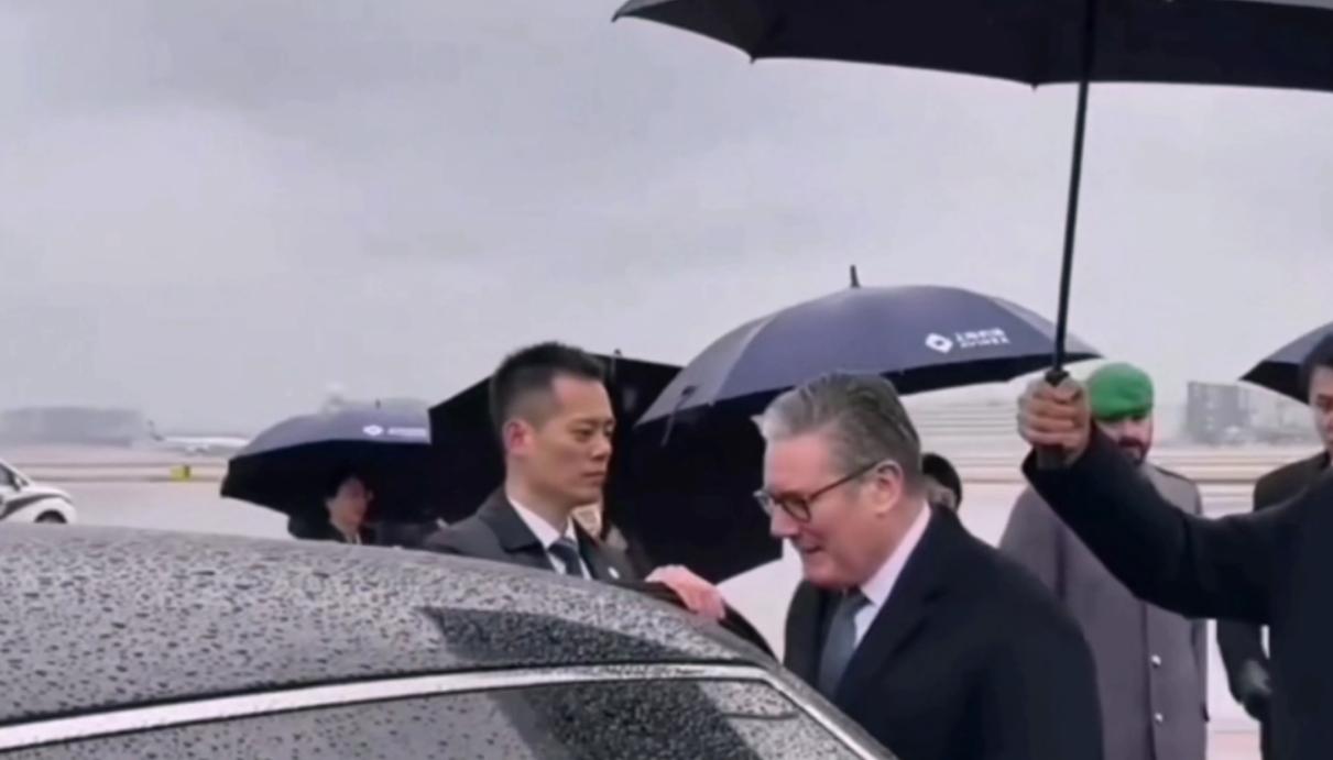 1月30日英国首相抵达上海，机场下着小雨地面都湿了，为他开车门的小伙却没有撑雨伞