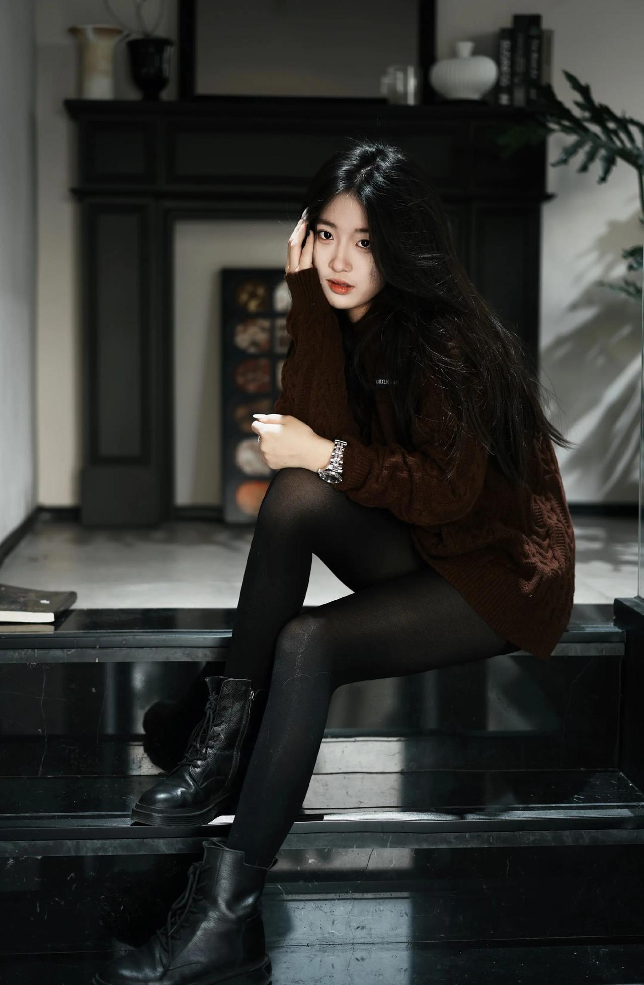 深棕色的粗针织毛衣，搭配黑色丝袜与黑色马丁靴，整体穿搭风格休闲随性又带有些许酷感