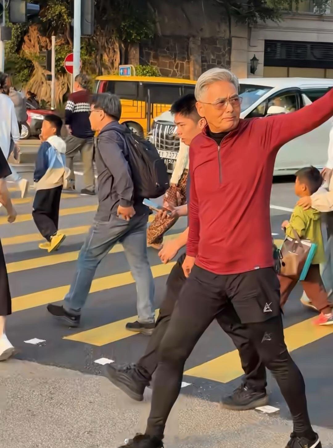 70岁周润发现身香港街头，他穿着红色外套，一头白发梳得一丝不苟，身材很高挑，即使