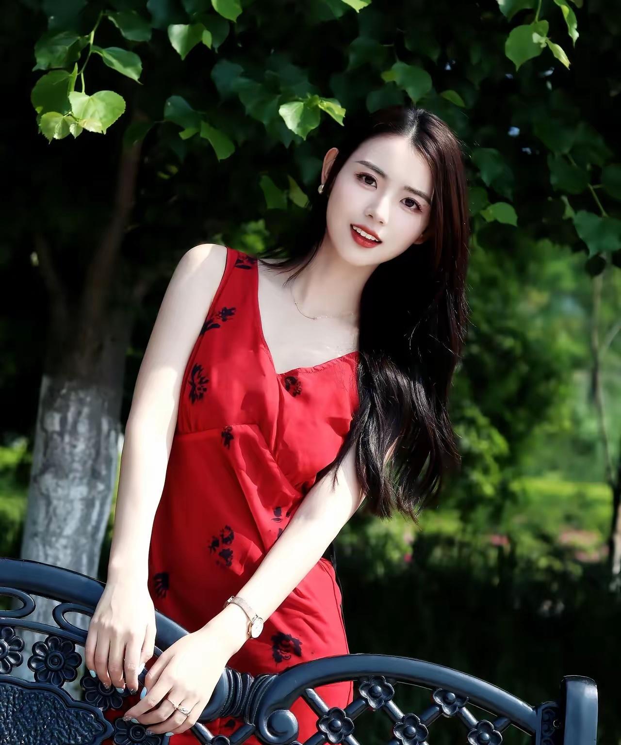 夏日红裙少女，绿意盎然背景，清新自然气息。