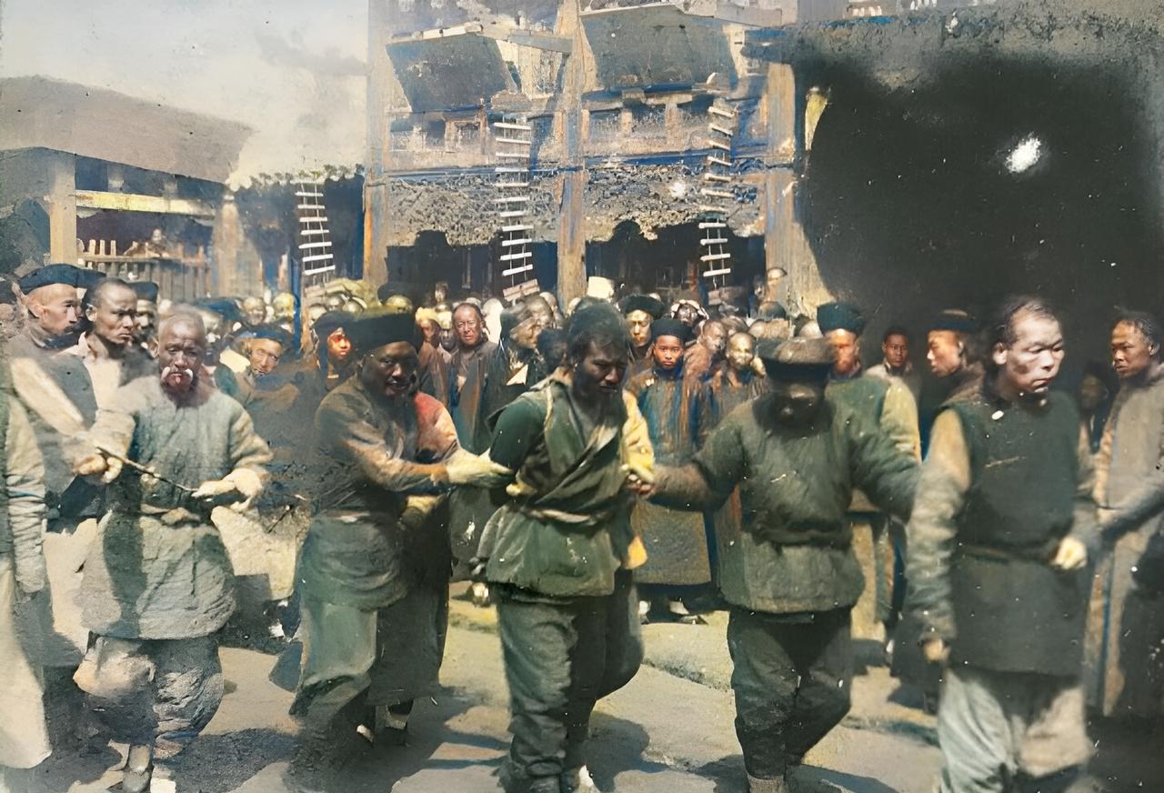 这是晚清一名死刑犯被绑缚着双手押着到达菜市口。当年,菜市口就在老北京鹤年堂药铺的