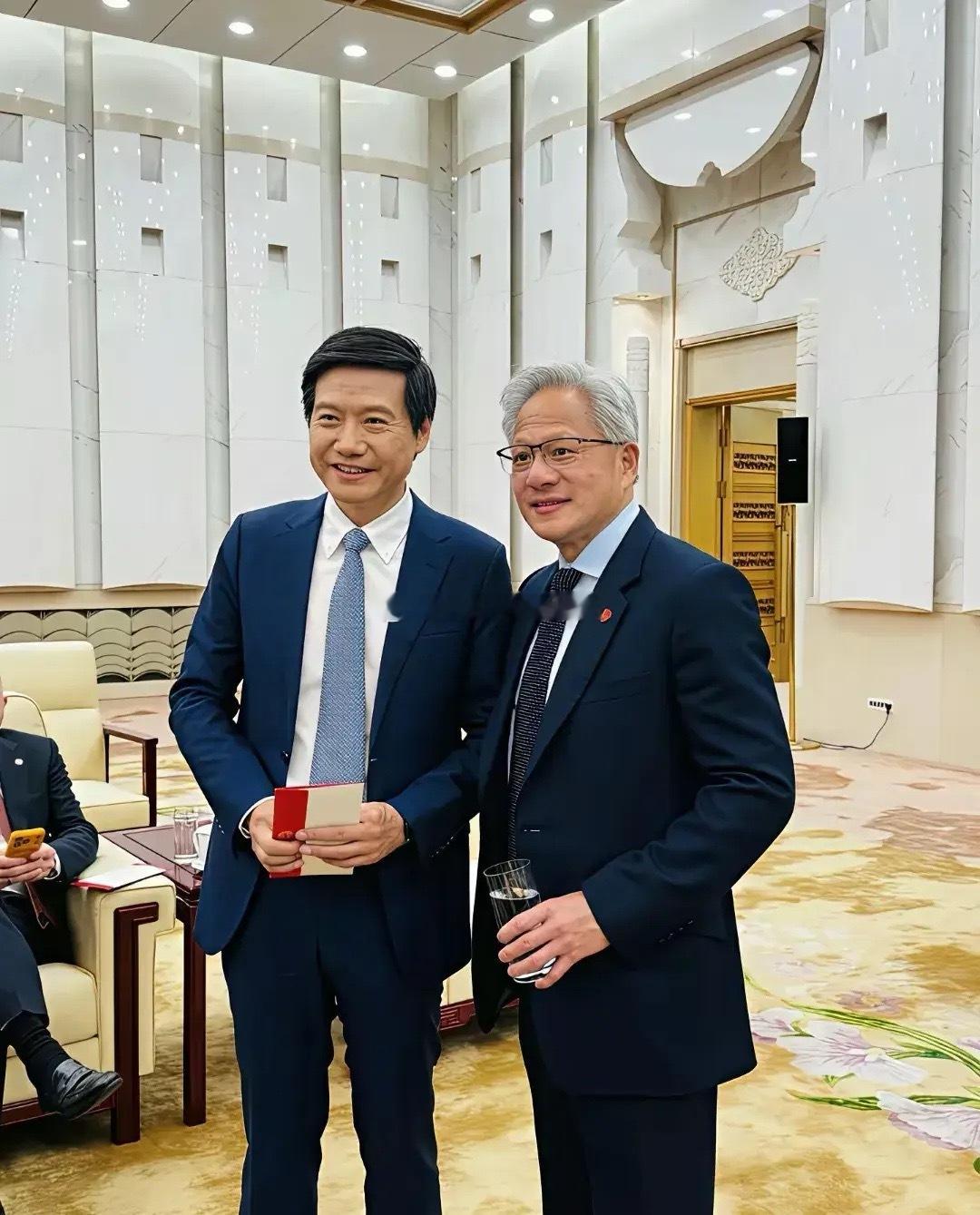 看下图，雷军和黄仁勋这次在人民大会堂见面合影，两人都站着，笑得多灿烂，他们既是朋
