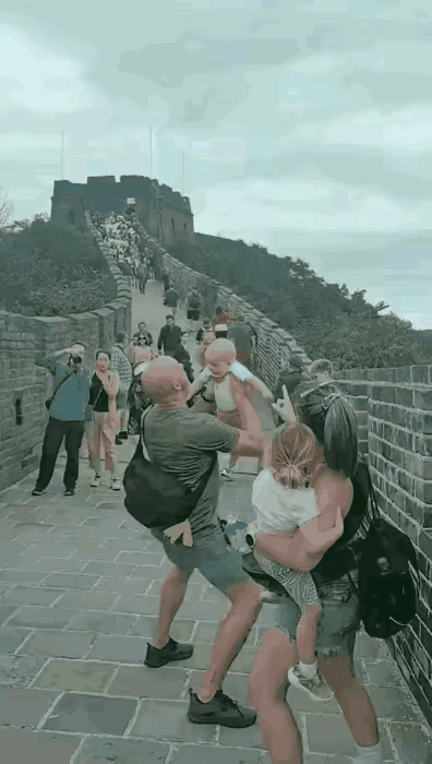 老外被中国的古建筑所感染，将孩子高高抛向空中。他的老婆在一旁一个劲儿地喊：“小点