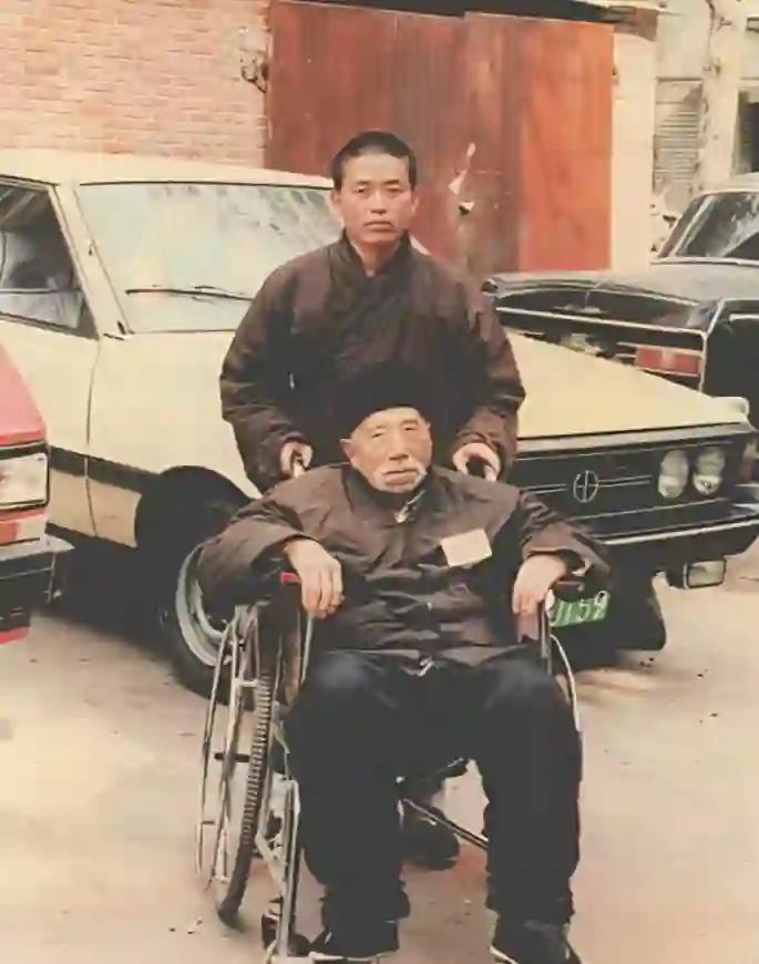 1986年，河南登封，21岁的释永信用轮椅推着师傅行正法师去看病。照片里他留着寸