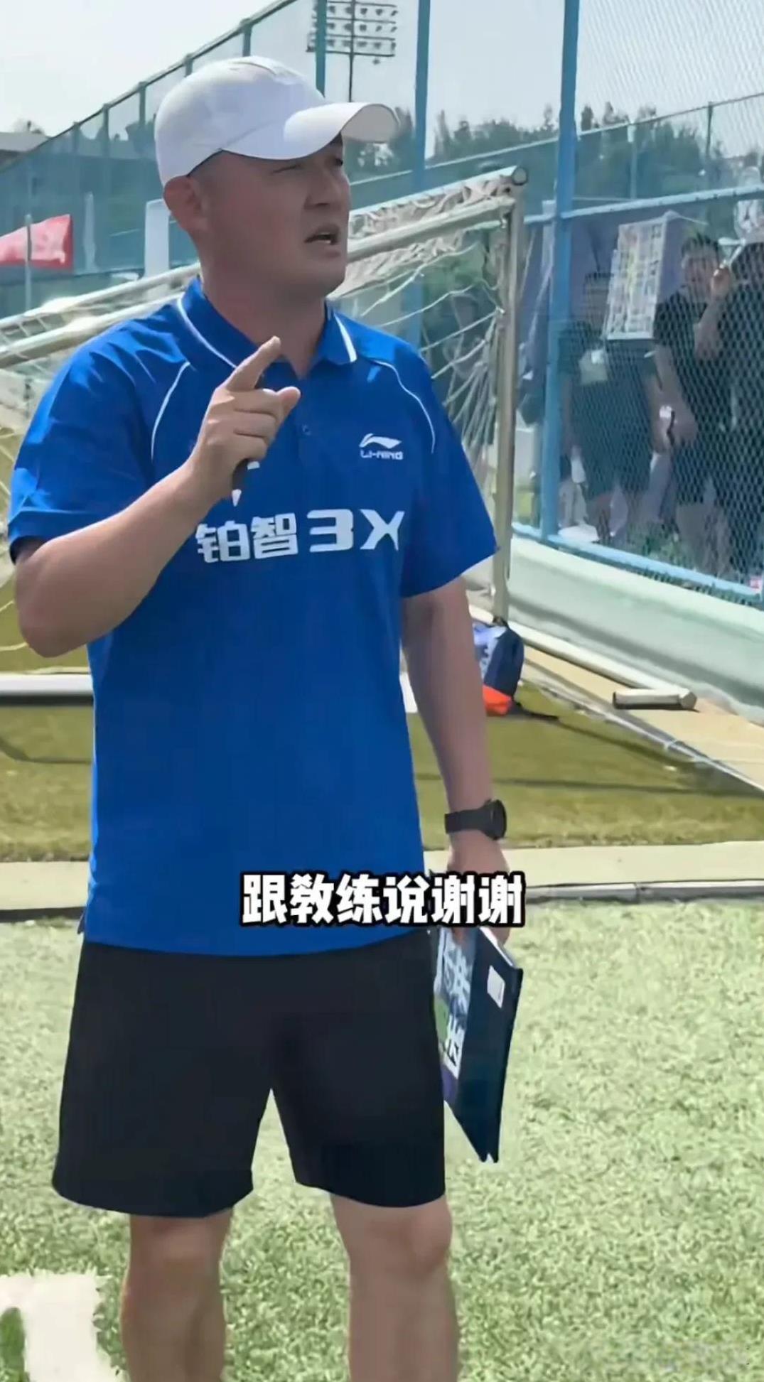 孙继海在足球场上看参加训练的新学生们从教练手里接过背心，看完后他很生气，让孩子们