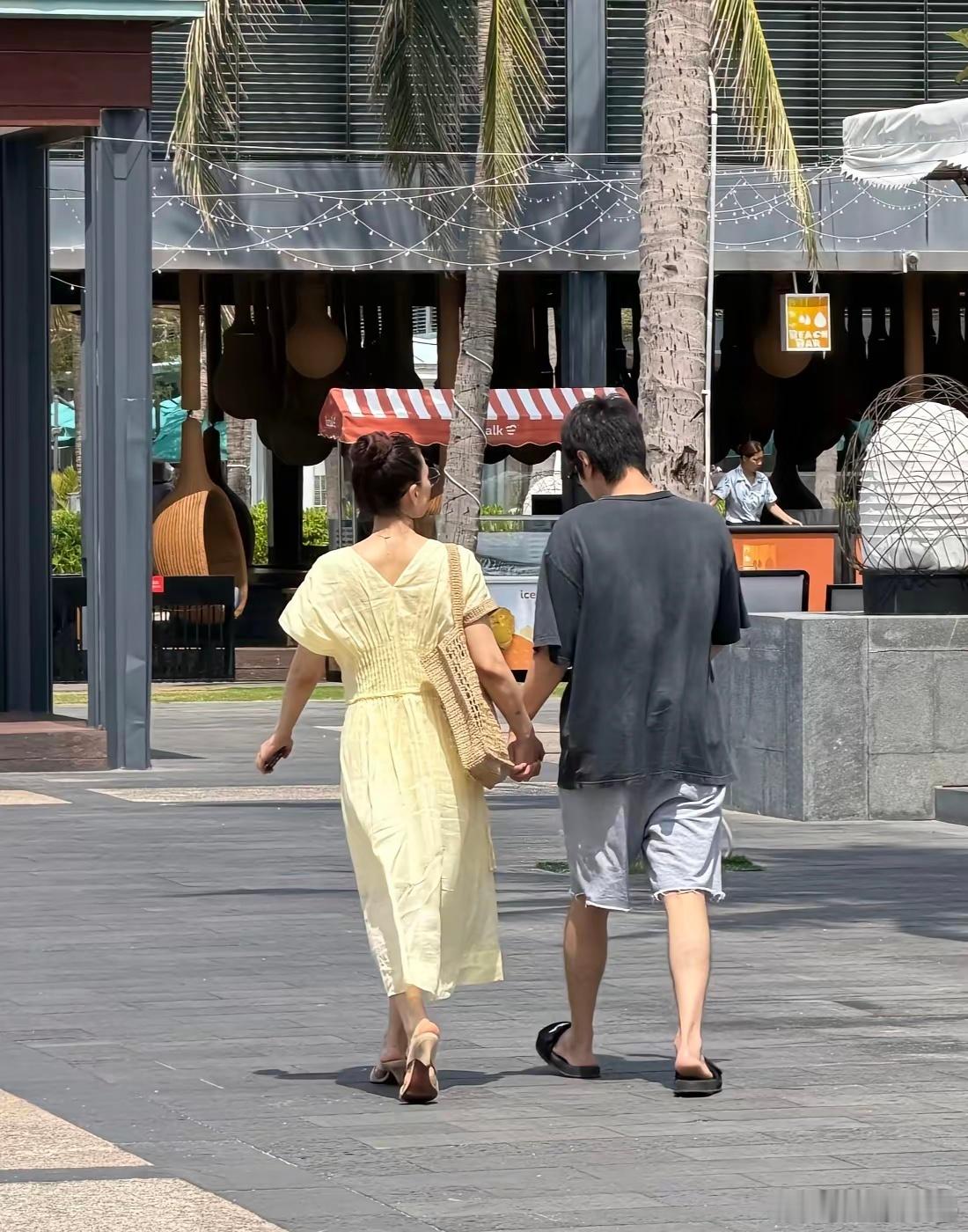 高圆圆和老公赵又廷在海南三亚牵手逛街被偶遇，她穿着一条淡黄色长裙，扎着丸子头，身