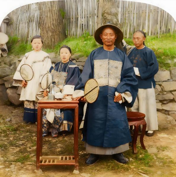 这张照片是清末一位官员与其家眷的合影，画面中央的官员身着清代官服，胸前的补子、头