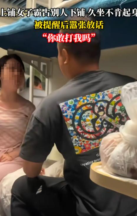 上铺女子霸占别人下铺不肯起身，下铺男子提醒她起来，不料，女子叫嚣：“我就坐这里怎