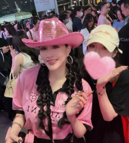 55岁钟丽缇现身新加坡看韩国女团演唱会，她穿着粉色上衣，戴着粉色帽子，整个人活力