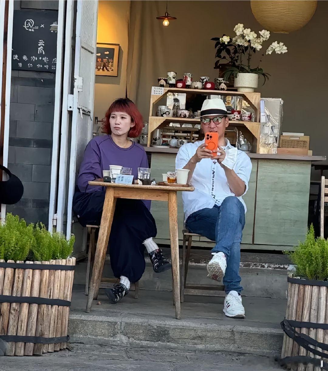55岁的周杰在云南大理被网友偶遇，他和一位美女在茶馆喝茶，他穿着白衬衫，头戴着帽