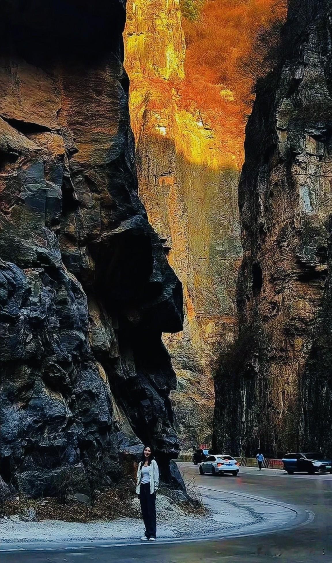 太行山两侧峭壁巍峨耸立，夕阳为远处的崖壁镀上滚烫的金橙。盘旋的公路穿梭于峡谷之间