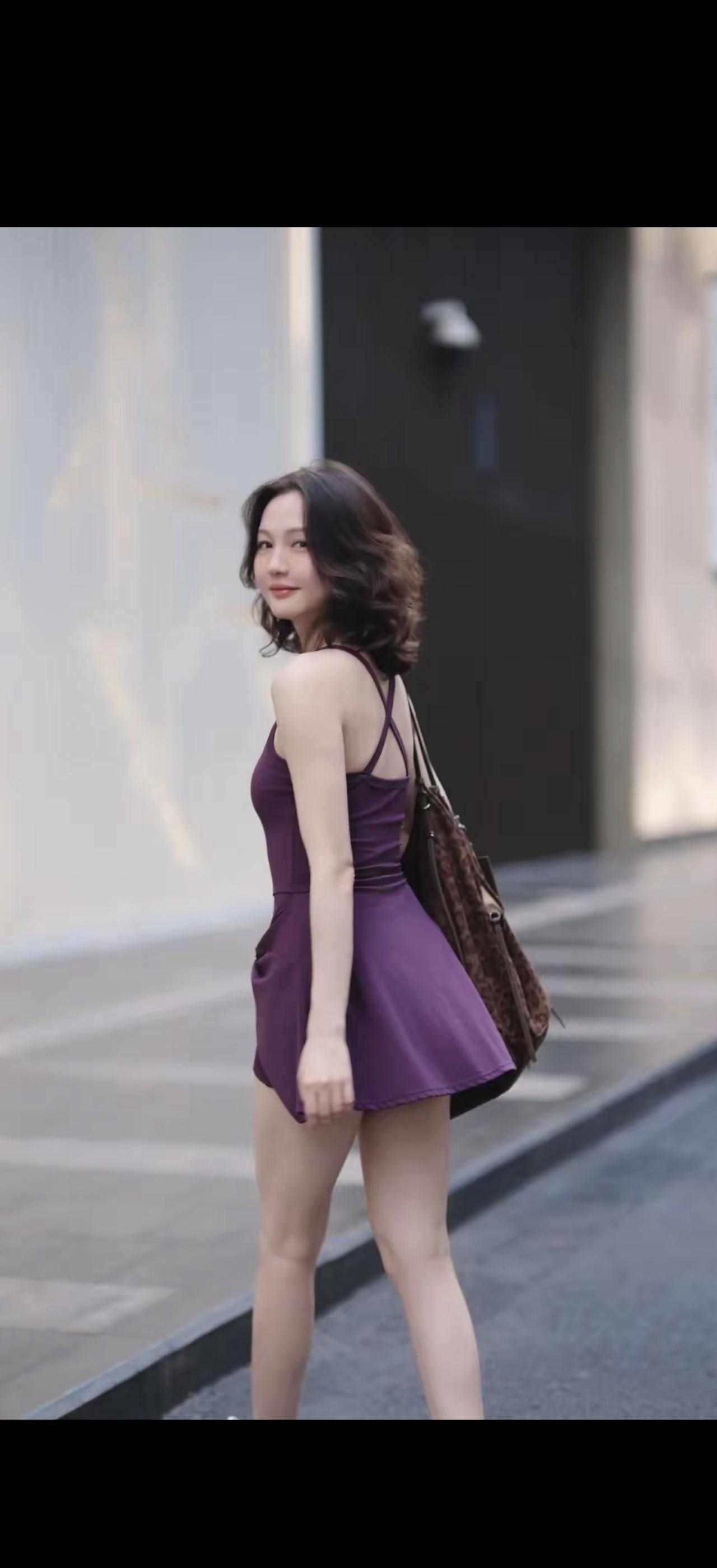 穿紫色裙子的女生在街上走着。