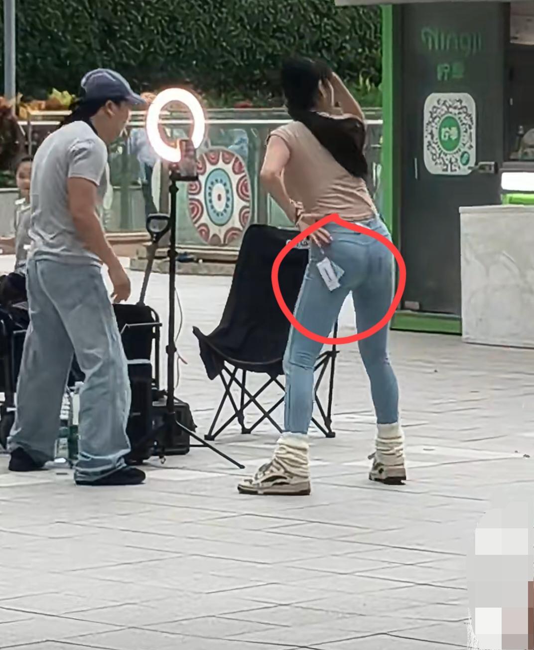 女主播穿着一条没有剪掉吊牌的牛仔裤，在镜头前给直播间的各位大哥们展示着她妖娆性感