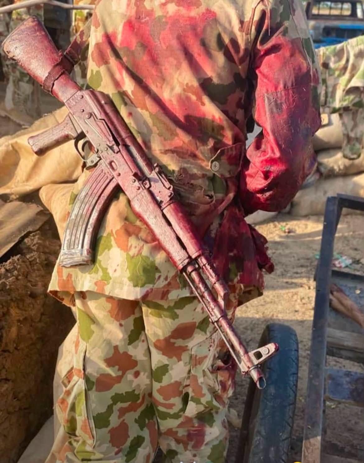 展示了一名身穿迷彩服、浑身浴血的尼日利亚士兵，步枪背在肩上，照片是从背后拍摄的，