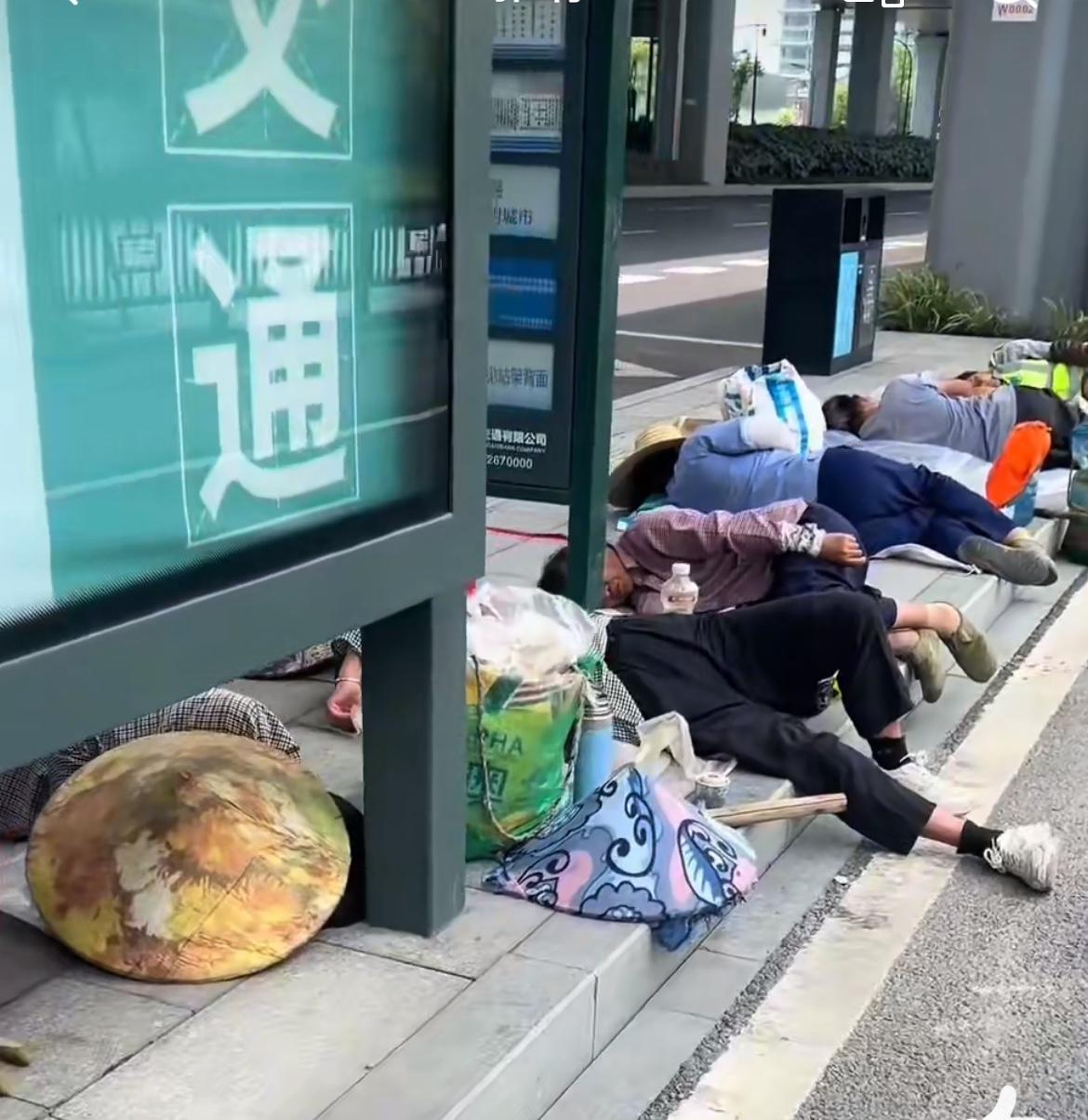 杭州一群民工35度高温公交车站躺地上睡觉，看到这个画面真难受。7月14日的杭州最