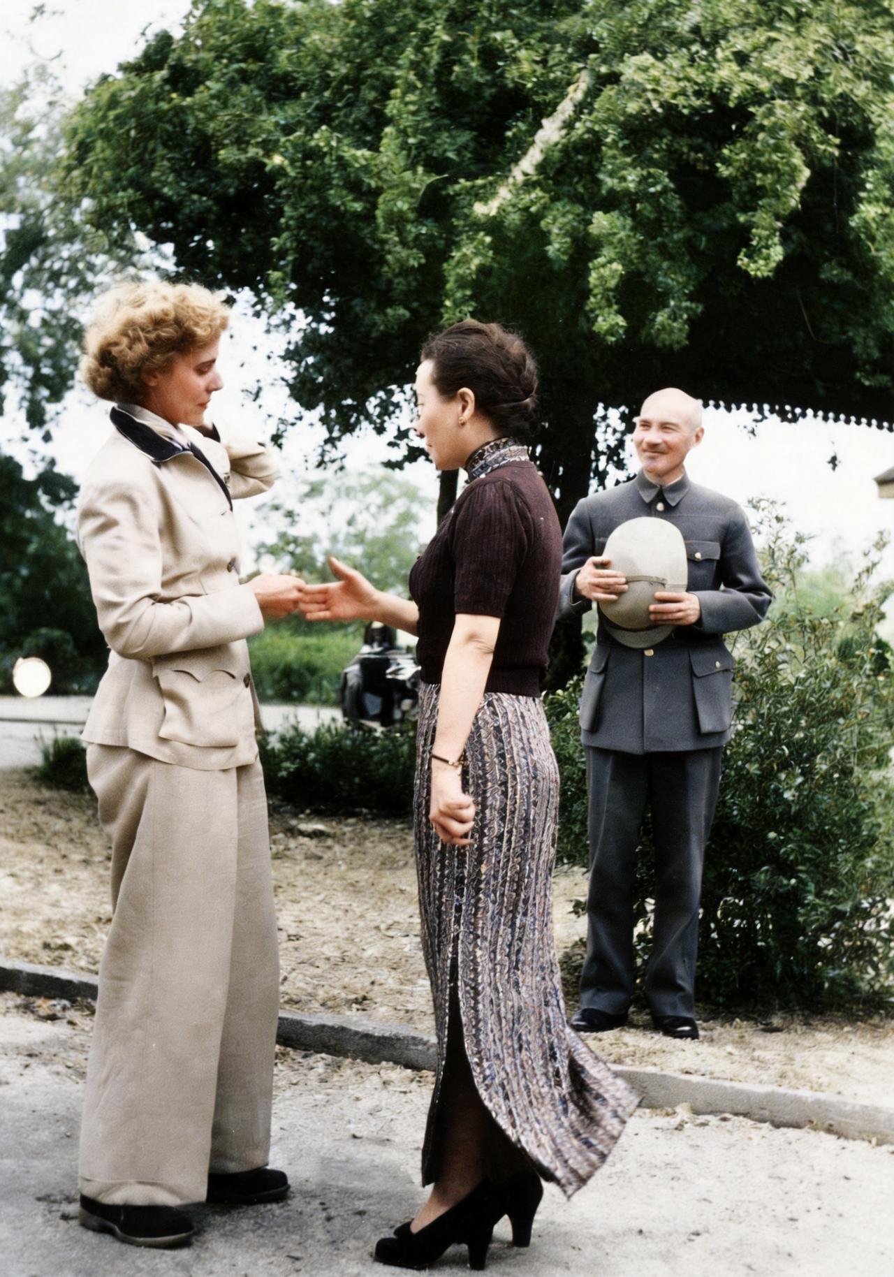 这是1942年宋美龄与美国剧作家克莱尔在花园里交谈。而蒋中正只能脸露微笑，静静地