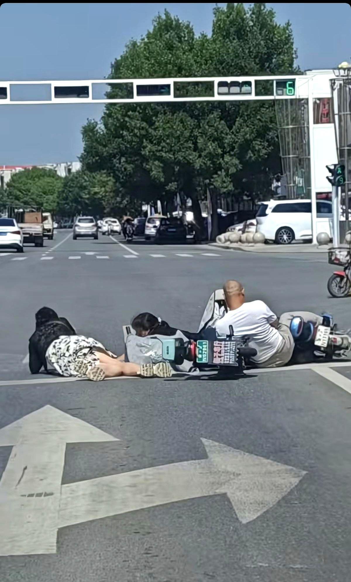 早高峰的十字路口人车涌动，监控拍到一位男骑手把电动摩托车横在斑马线上，车把锁得死
